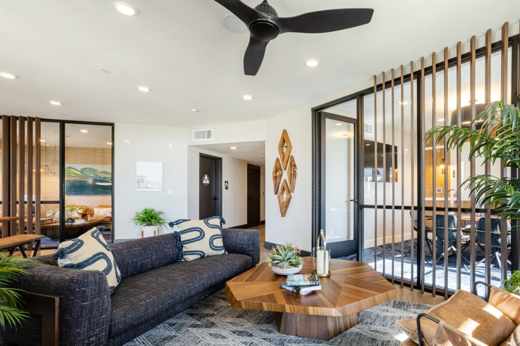 Clubhouse lounging area with couches, seating, wood-style flooring, and ceiling fan