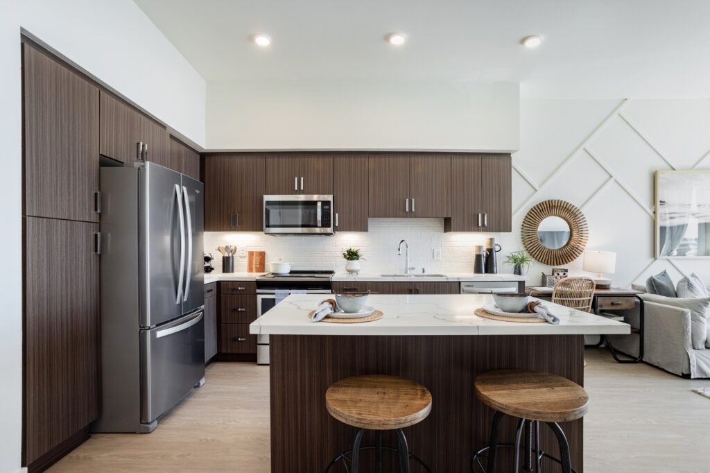 Kitchen area with island, dual sink, steel appliances, wood cabinets, and wood-style flooring