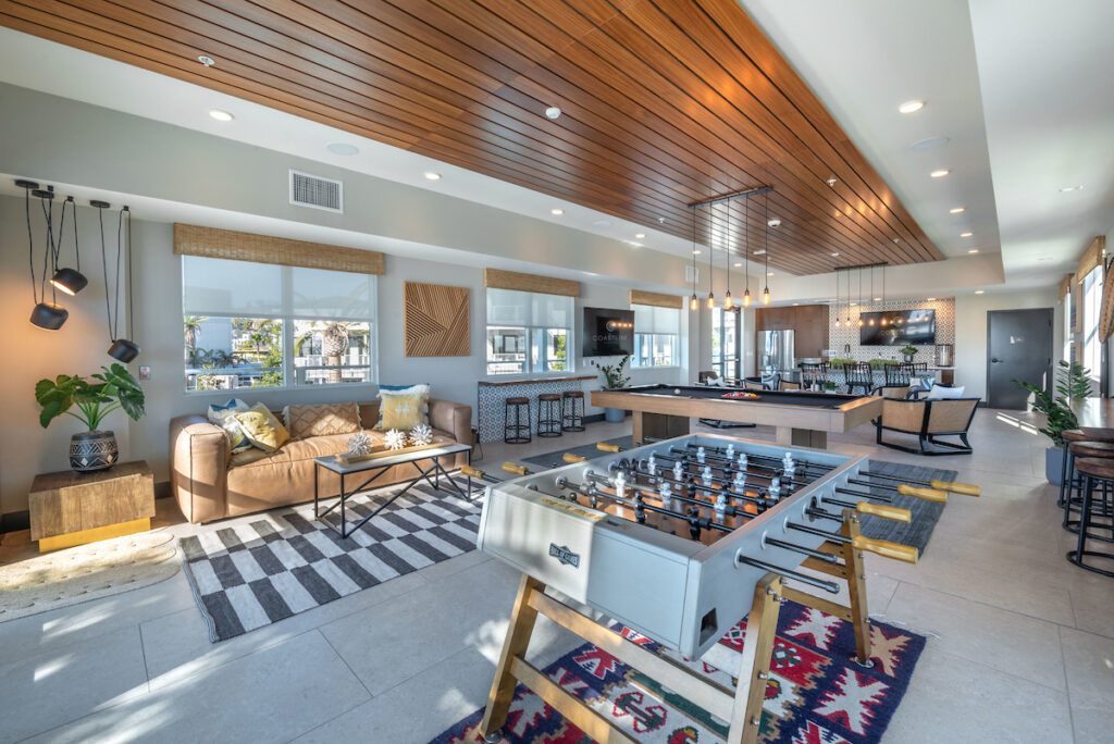 Clubroom with foosball, variety of seating, barstools, pool table, flat screen TVs, and decorative lighting