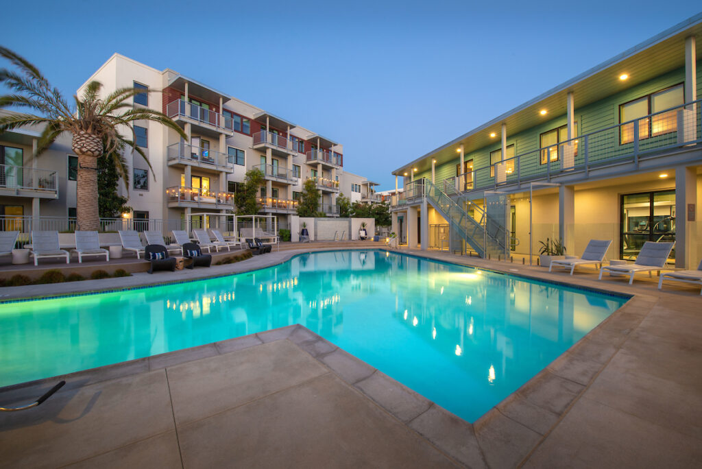 Evening shot of resort style pool with lounge style seating and tropical landscaping.