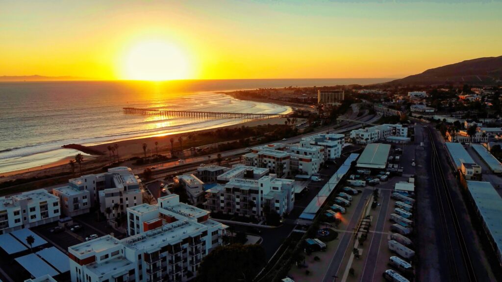 Aerial view overlooking pier, beach, and ocean with sunset