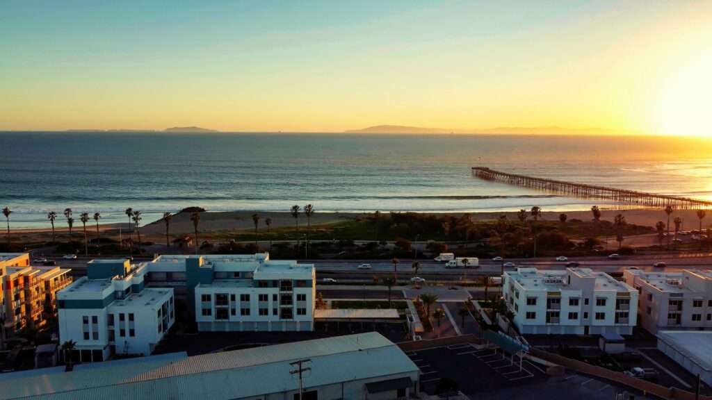Aerial view overlooking pier, beach, and ocean with sunset