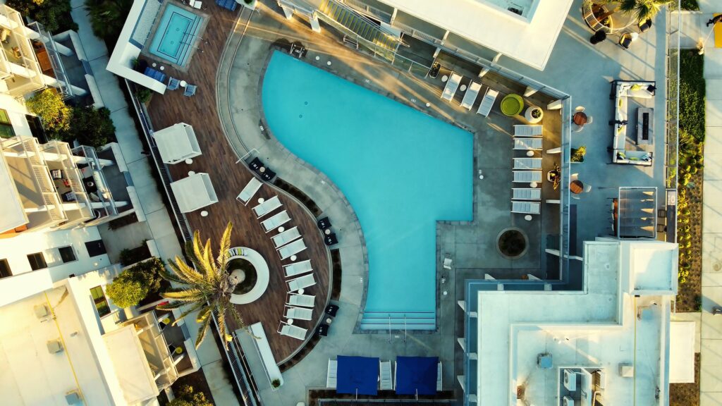 Aerial view of pool, hottub, and outside courtyard with tropical landscaping and lounge seating